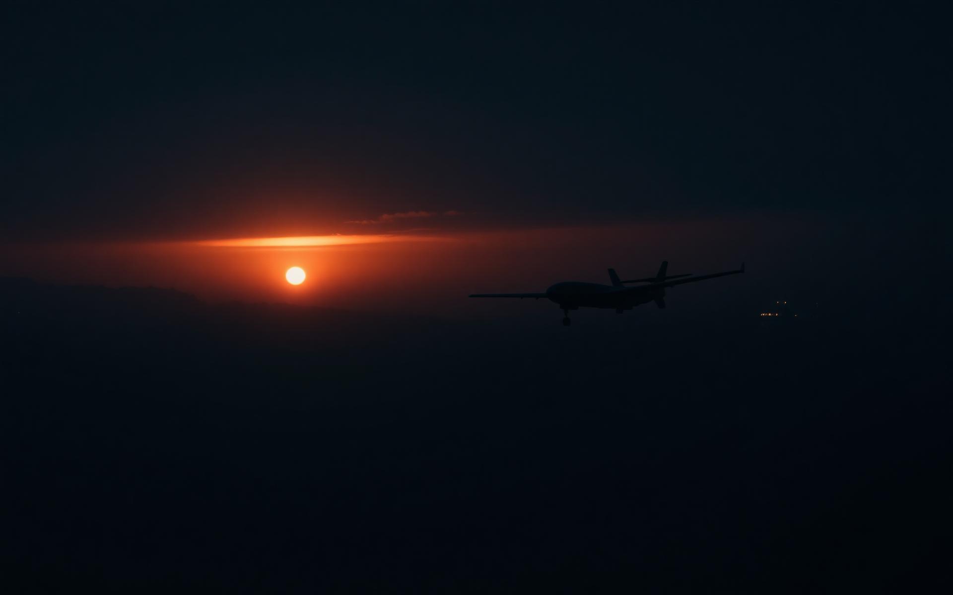 Fixed-wing interceptor UAV silhouette above open water at dusk